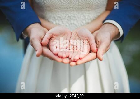 Lo sposo e gli sposi tengono gli anelli nei loro palmi. Matrimonio. Foto Stock