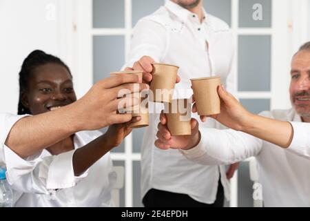 Sorridi giovani uomini d'affari internazionali mentre si siedono insieme pausa caffè in ufficio Foto Stock