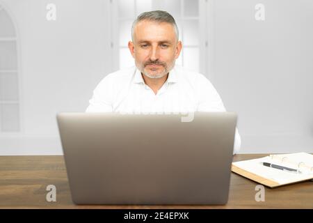 Professionisti IT che leggono informazioni di testo dal sito Web su un dispositivo portatile connesso a Internet wireless. Concentrato giovane uomo che guarda il tirocinio Foto Stock