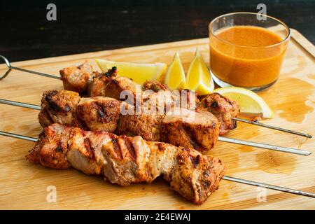 Pinchos Morunos - Kebab di maiale spagnolo: Pezzi marinati di filetto di maiale alla griglia su spiedini e serviti con paprika aioli e spicchi di limone Foto Stock