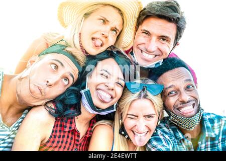 Amici multirazziali che prendono selfie pazzo con maschere aperte - Nuovo concetto di amicizia normale con i giovani che si divertono insieme Foto Stock
