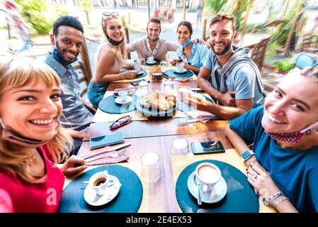 Amici che prendono selfie al caffè bar bere cappuccino con aperto Maschere facciali - persone che si divertono insieme nella caffetteria esterna Foto Stock