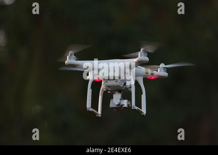 24 - Video drone di sorveglianza a quadropter bianco con sfondo scuro. Anche il soggetto isolato che utilizza la messa a fuoco selettiva si distingue per il colore della luce. Foto Stock