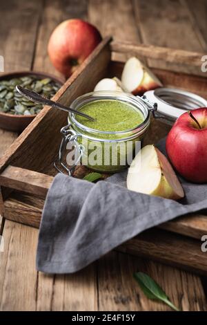 Snack sano ricco di minerali, burro di semi di zucca fresco senza nocciole in un vaso di vetro su sfondo di legno Foto Stock