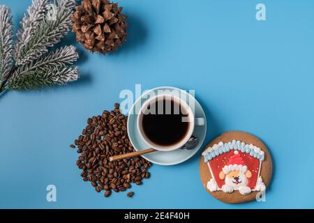 Tazza di caffè nero, chicchi di caffè e pan di zenzero su sfondo blu, spazio di copia per il testo. Concetto di Natale. Foto Stock