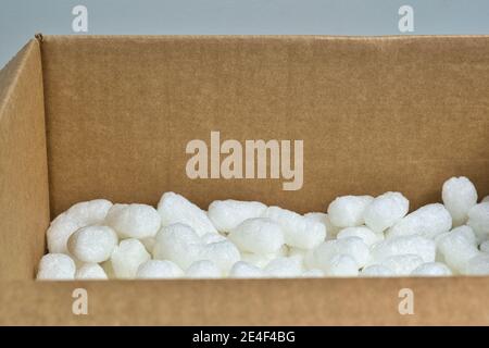 Imballaggio bianco arachidi styrofoam materiale di imballaggio popcorn all'interno di una scatola di cartone, vista angolare con spazio di copia. Foto Stock