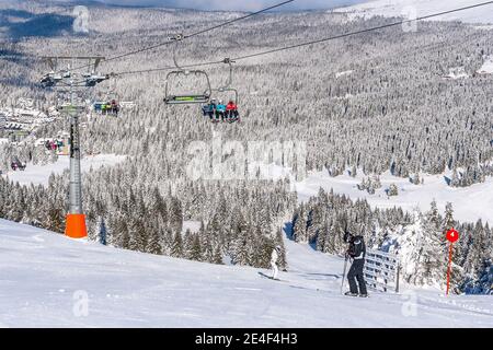 Kopaonik, Serbia - 22 gennaio 2016: Piste da sci, persone sugli impianti di risalita, montagne, case ed edifici panorama Foto Stock