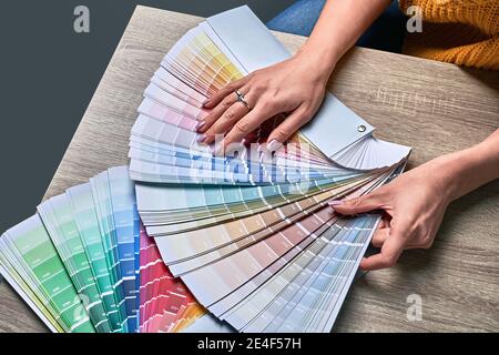 Ruota dei colori per scegliere il tono di vernice. Mani di designer di interni femminili che lavorano con la tavolozza per la scelta dei colori. Concetto di processo creativo. Confronto Foto Stock