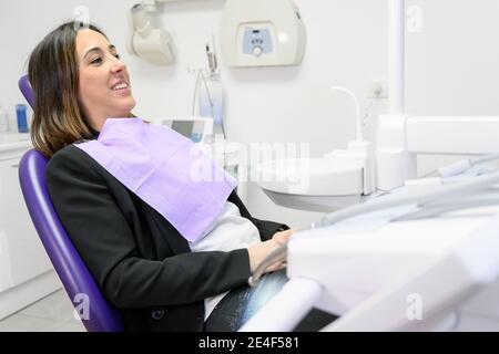 Ritratto di giovane donna sorridente sdraiata in sedia dentale con spazio copia. Foto di alta qualità Foto Stock