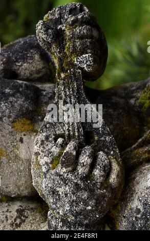 Un lichene e muschio coperto vecchia statua di pietra di un cherubino mani che tengono una lira, stringed strumento, sui terreni del Castello di Hatley a Colwood, British Foto Stock