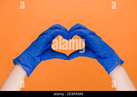Mani maschili in guanti in lattice di protezione medica simbolo del cuore come un modo per mostrare gratitudine ai medici e. infermieri per aiuto Foto Stock