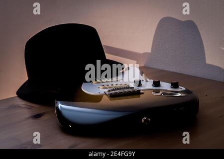 Una sera una chitarra elettrica e un cappello nero su un tavolo. Foto Stock