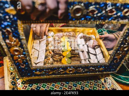 Donna mano aperta di lusso bella scatola intarsiata con gioielli con gustosi dolci indiani caramelle all'interno del tradizionale henné mehndi sangeet serata di festa Foto Stock