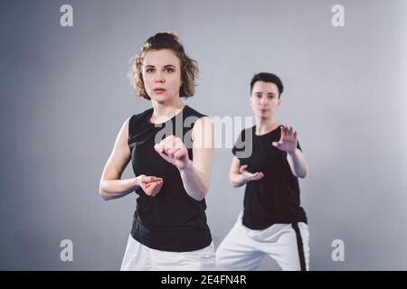 Allenatore insegna all'atleta a colpire il calcio. Forti atleti di arti marziali femminili nella loro formazione taekwon-do. Due giovani donne istruttore e studente che pratica Foto Stock