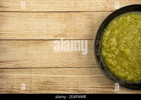 un piatto nero di zuppa di crema verde vegetale fresca servita su sfondo rustico, cibo Foto Stock