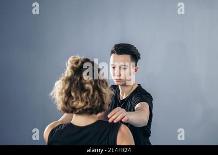 L'istruttore di taekwondo femminile conduce una sessione di allenamento personale per la giovane donna in palestra. Ragazza che padroneggia il nuovo taekwondo si muove durante la classe con allenatore. Exe Foto Stock