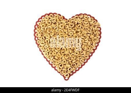primo piano di cereali per la colazione con cerchi e cuori su rosso merletto cuore isolato doily su bianco Foto Stock