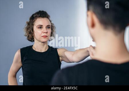 Allenatore insegna all'atleta a colpire il calcio. Forti atleti di arti marziali femminili nella loro formazione taekwon-do. Due giovani donne istruttore e studente che pratica Foto Stock
