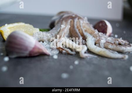 Tentacoli calamari su un piatto di ardesia con limone e aglio Foto Stock