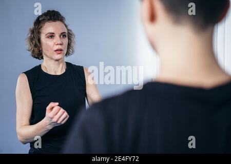 Giovane donna allieva con il suo allenatore in palestra. Taekwondo allenatore che insegna donna adulta in allenamento personale. Due donne che praticano arti marziali Figh Foto Stock