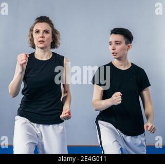 L'istruttore di taekwondo femminile conduce una sessione di allenamento personale per la giovane donna in palestra. Ragazza che padroneggia il nuovo taekwondo si muove durante la classe con allenatore. Exe Foto Stock