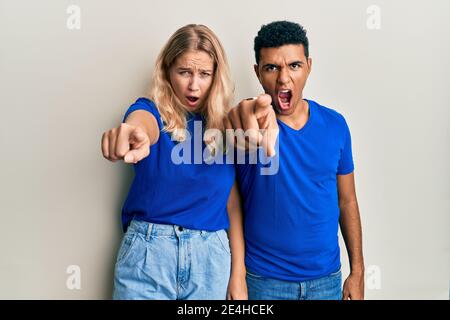Giovane coppia interracial che indossa abiti casual puntando dispiaciuto e frustrato alla macchina fotografica, arrabbiato e furioso con voi Foto Stock