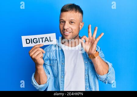 Bell'uomo muscolare tenendo parola digitale su carta facendo segno ok con le dita, sorridente amichevole gesturing simbolo eccellente Foto Stock