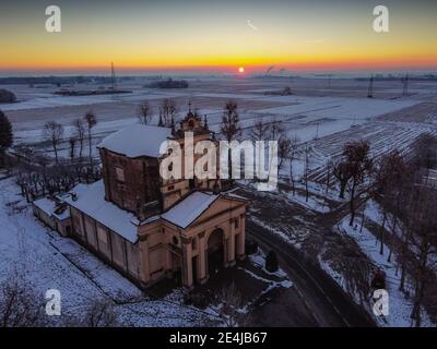 Sole che sorge sulla pianura innevata e il santuario di Varallino di Galliate, Novara, Piemonte, Italia Foto Stock