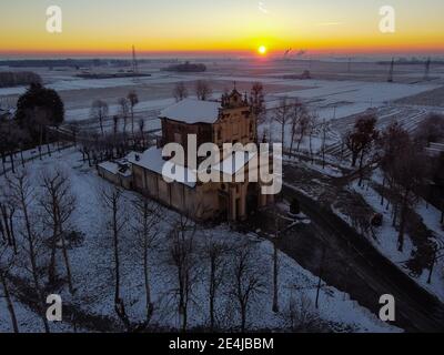 Sole che sorge sulla pianura innevata e il santuario di Varallino di Galliate, Novara, Piemonte, Italia Foto Stock