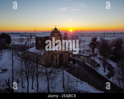 Sole che sorge sulla pianura innevata e il santuario di Varallino di Galliate, Novara, Piemonte, Italia Foto Stock