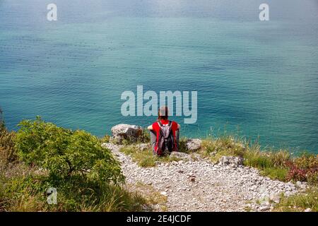 Una donna che guarda il mare adriatico dal bordo carsico vicino Trieste, Italia Foto Stock