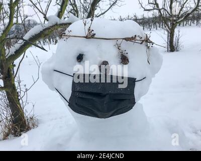 Pupazzo di neve con maschera facciale in tempo corona Foto Stock