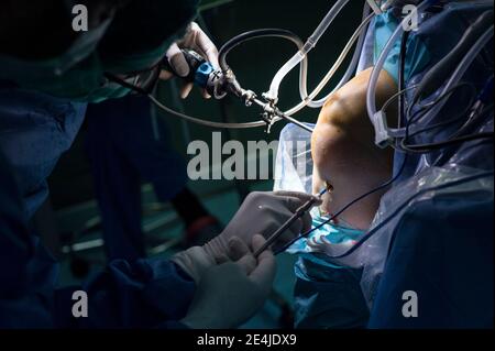 Chirurgo ortopedico maschile concentrato che opera con collaboratore in terapia intensiva Foto Stock