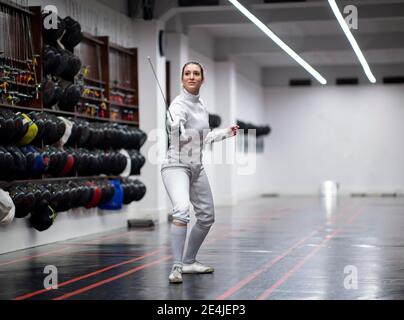 Donna in scherma vestito che pratica in palestra Foto Stock