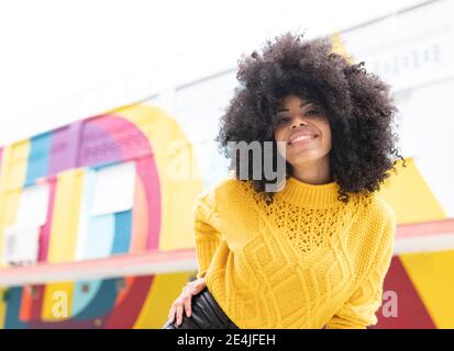 Giovane donna sorridente mentre si alza in piedi all'aperto Foto Stock