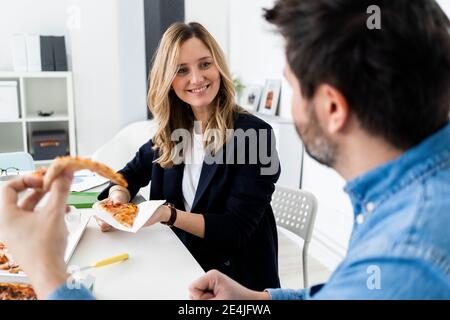 Uomini d'affari che mangiano la pizza e parlano in ufficio durante la pausa Foto Stock