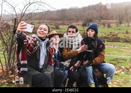 Famiglia con il cane che prende selfie nel paesaggio autunnale Foto Stock