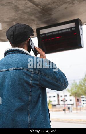 Uomo d'affari in chiamata mentre si è in piedi sulla fermata dell'autobus Foto Stock