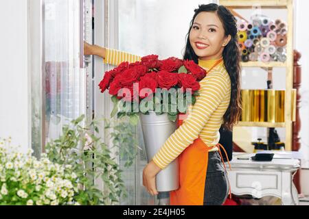 Fiorista che mette rose in mostra floreale Foto Stock