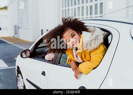 Ragazza allegra che sbirciando attraverso la finestra mentre si viaggia in auto Foto Stock