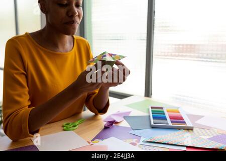 Artista Origami seduto in studio che lavora con carta colorata Foto Stock