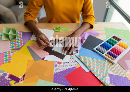 Artista Origami seduto in studio pieghevole carta colorata Foto Stock