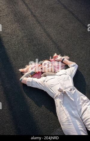 Giovane donna hipster con gli occhi chiusi sdraiati nello sport campo Foto Stock