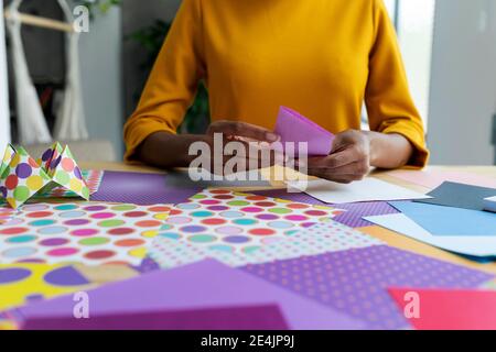 Artista Origami seduto in studio pieghevole carta colorata Foto Stock