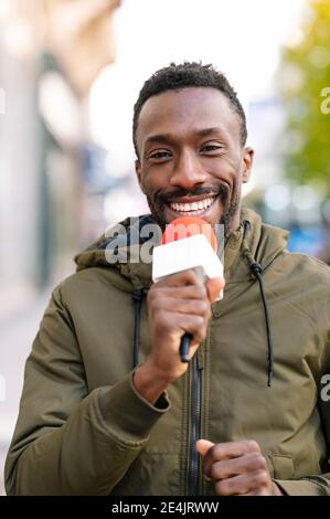 Primo piano di un presentatore sorridente che parla al microfono Foto Stock