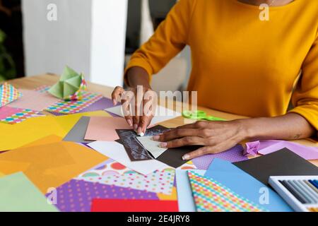 Artista Origami seduto in studio pieghevole carta colorata Foto Stock