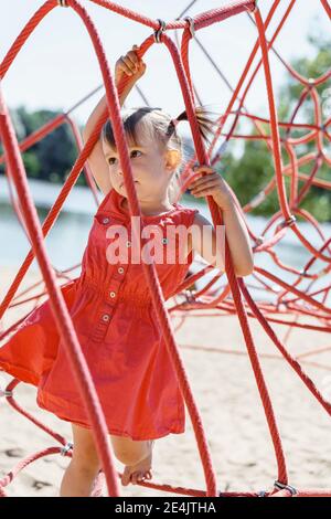 un bambino sale su una ragnatela nel parco giochi. Foto Stock