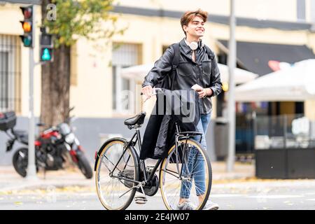 Felice giovane uomo che cammina in bicicletta sulla strada in città Foto Stock