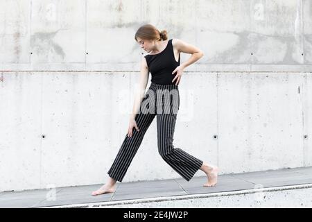 Ballerina in pantaloni a righe nere davanti alla parete in cemento Foto Stock