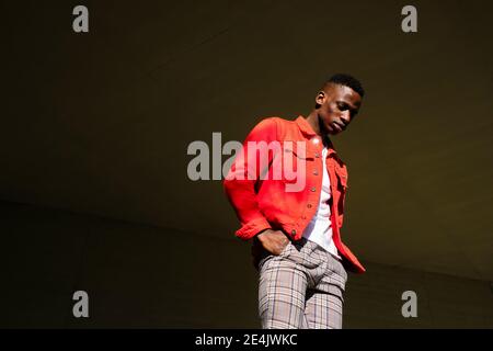 Elegante giovane uomo con giacca rossa e pantaloni controllati all'aperto Foto Stock